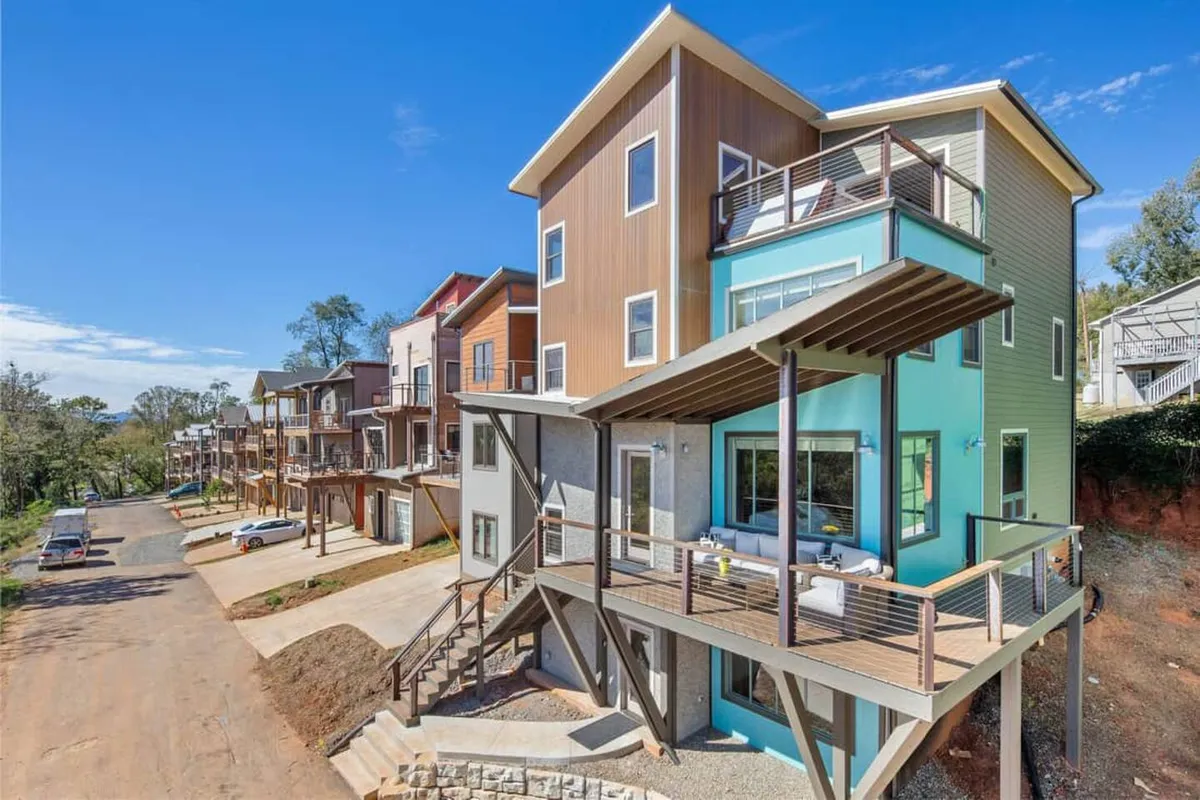 Featuring modern exterior architecture, this image highlights a spacious deck area with colorful touches. The deck invites guests to relax or socialize while taking in vibrant sunsets or tranquil mornings. The surrounding landscape enhances the sense of indoor-outdoor living.