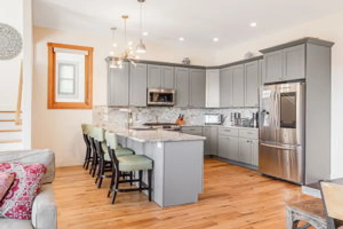 A spacious, open-concept kitchen with a large island, stainless steel appliances, and contemporary light fixtures. The area is bright, inviting, and perfect for cooking or entertaining together.