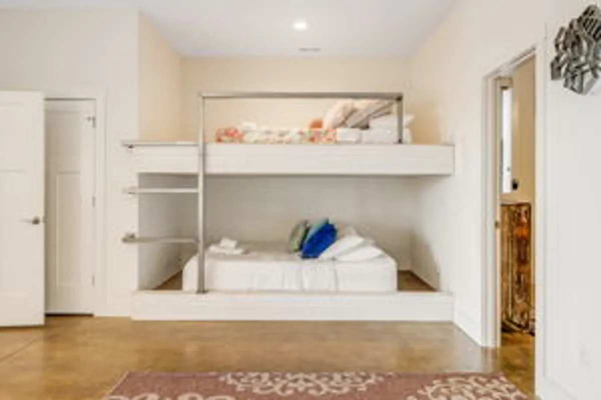 A cozy bedroom with bunk beds, a decorative rug, and lots of pillows. The space feels designed with families and children in mind, offering a playful, flexible sleeping arrangement and a cheerful, cozy atmosphere.